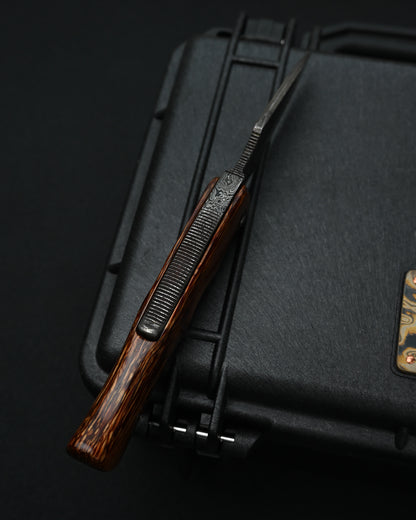 Detailed view of the one-piece natural wood handle on a Kazushi Machida handmade Higonokami-style knife, highlighting its rich grain.