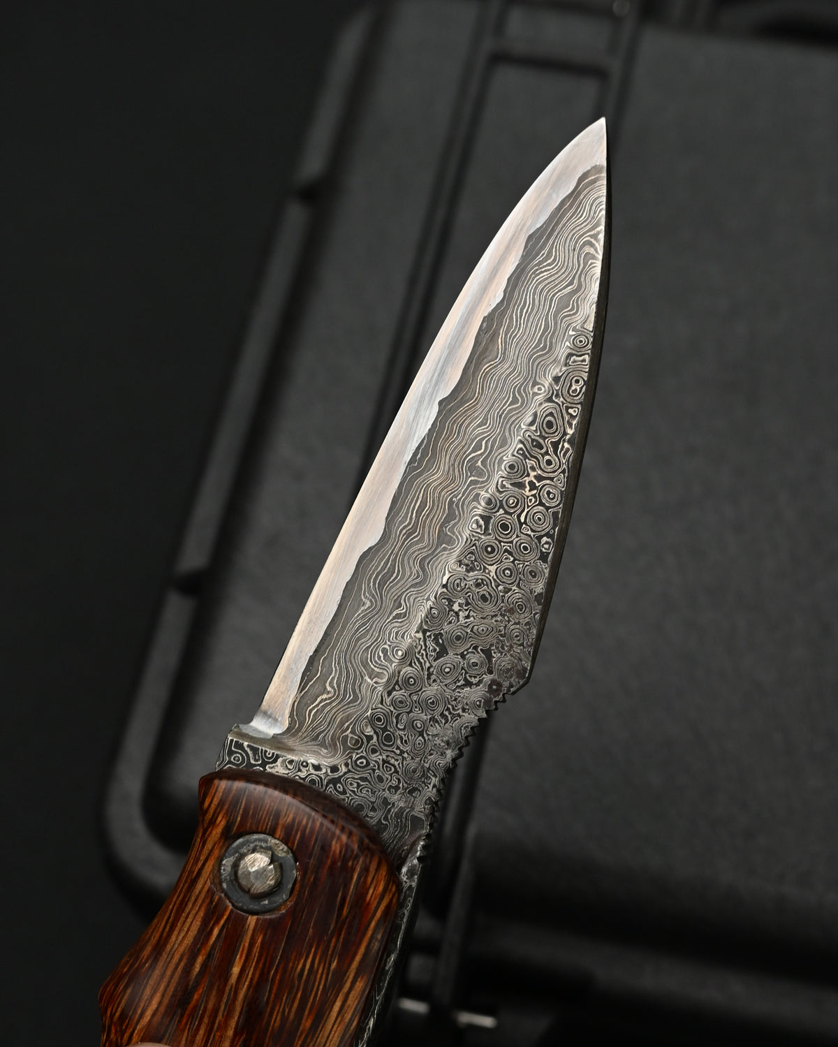 Close-up of the intricate Damascus steel patterns on a Japanese folding knife personally forged by custom knifemaker Kazushi Machida.