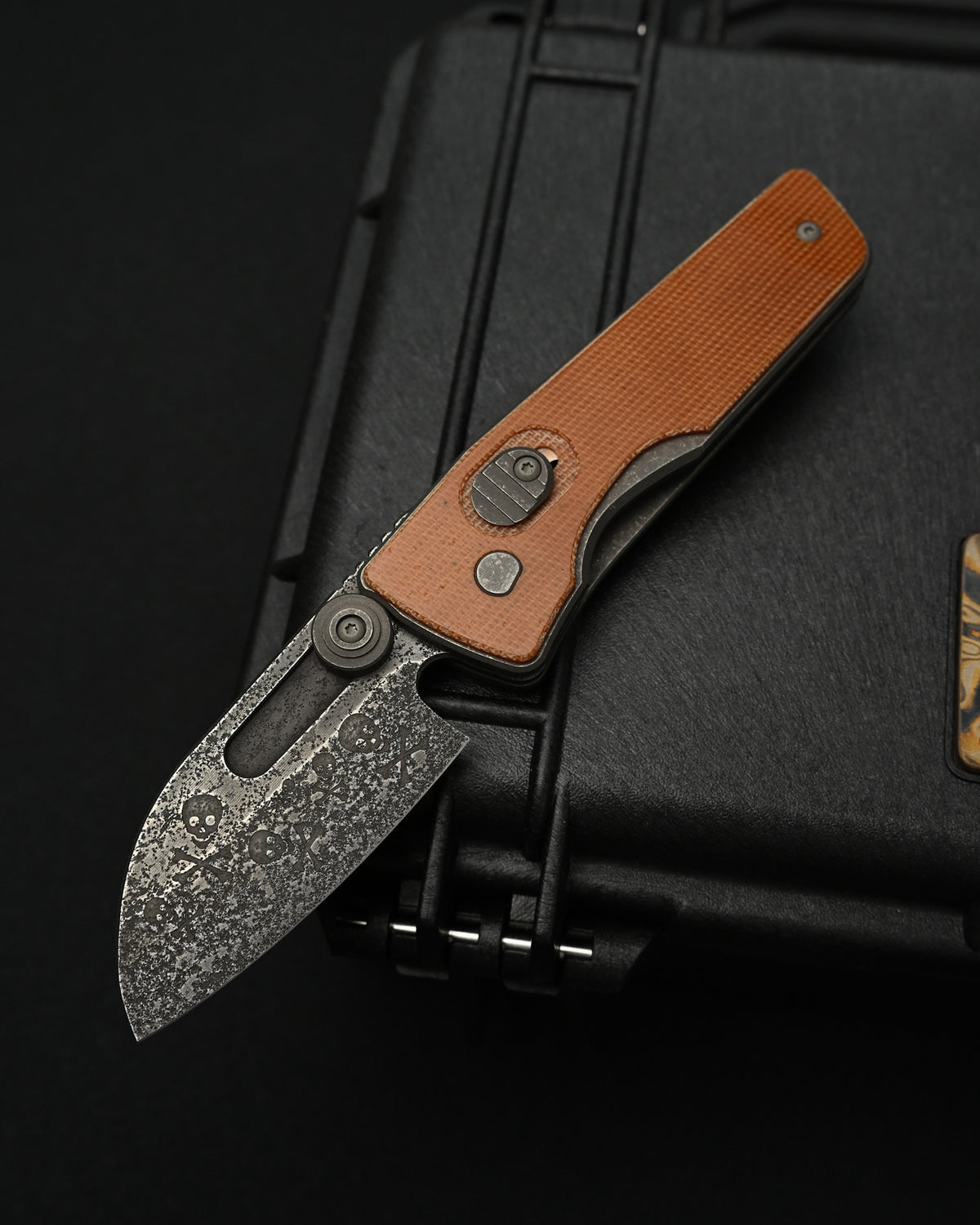 Serge Knives Guppy Custom folding knife featuring all-over recessed skull engravings on a weathered W2 carbon steel blade, titanium and vintage Westinghouse Micarta handle, heat-colored titanium pocket clip, made in the USA