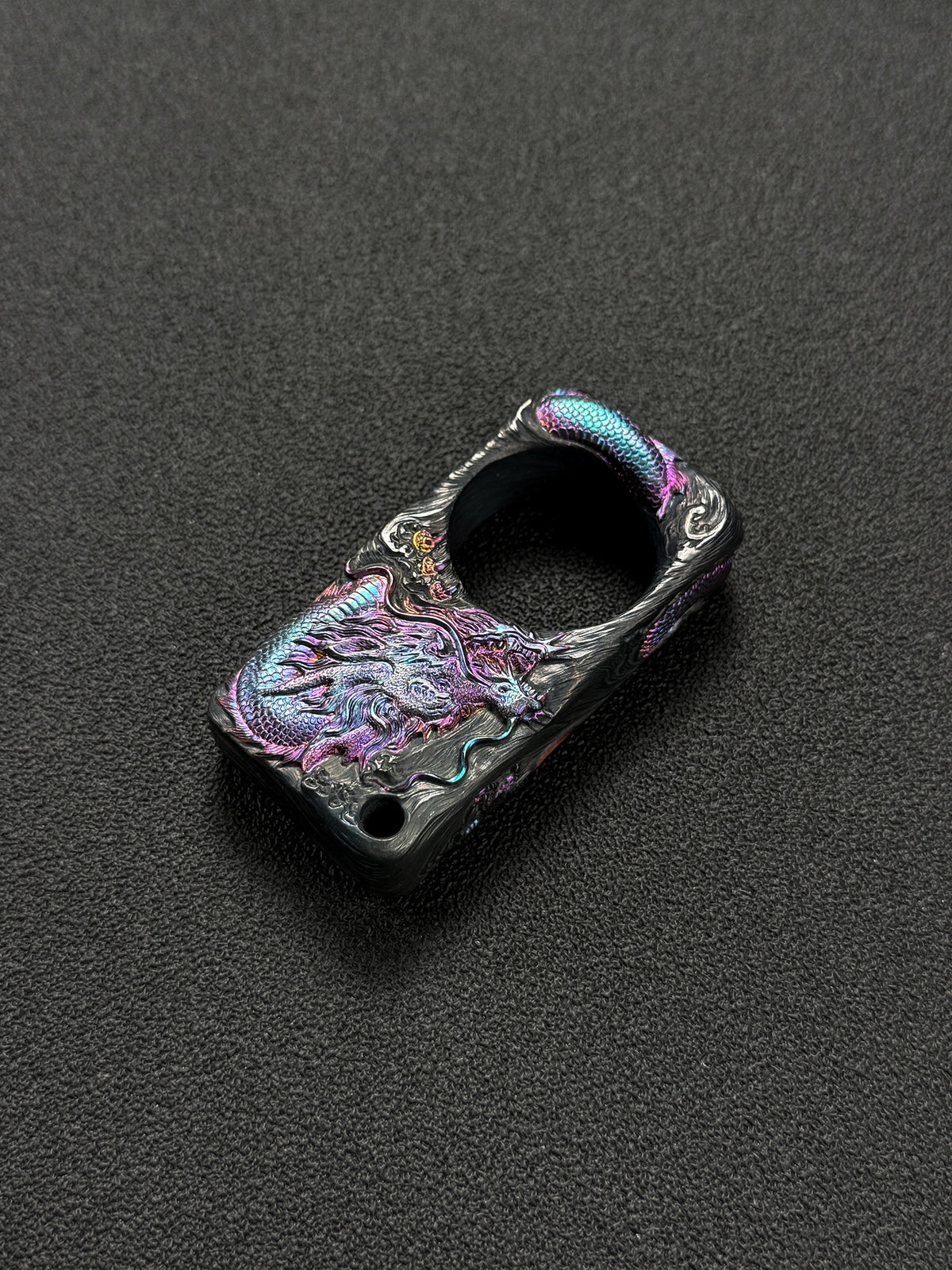 Sunizumi custom hand-engraved titanium dragon artwork featuring a coiled Eastern dragon with iridescent purple and blue scales, flowing metal textures, and a circular central opening