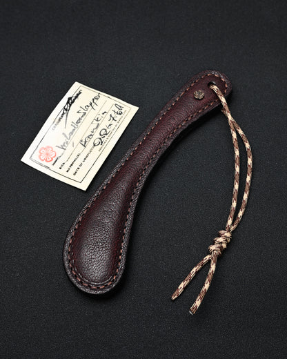 Sunizumi Shoten × Wtopia burgundy bear leather EDC paddle featuring genuine bear leather, internal steel plate, Wtopia bronze apricot blossom embellishment, and 550 paracord, made in Japan