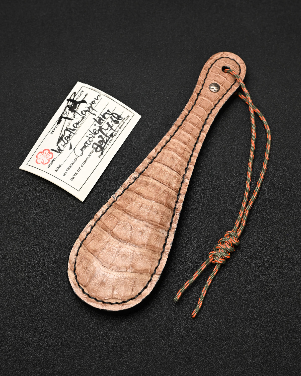 Sunizumi Shoten × Wtopia 250mm khaki crocodile leather EDC paddle featuring genuine crocodile leather, internal steel plate, bronze emblem with silver inlay, and 550 paracord lanyard, made in Japan
